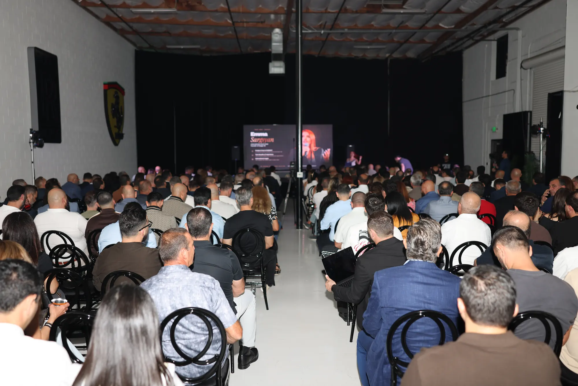 The room at The Reserve from the back, every seat taken, with the host on the big screen
