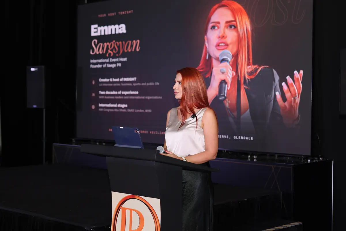 The host at the podium with her walk-on screen behind her